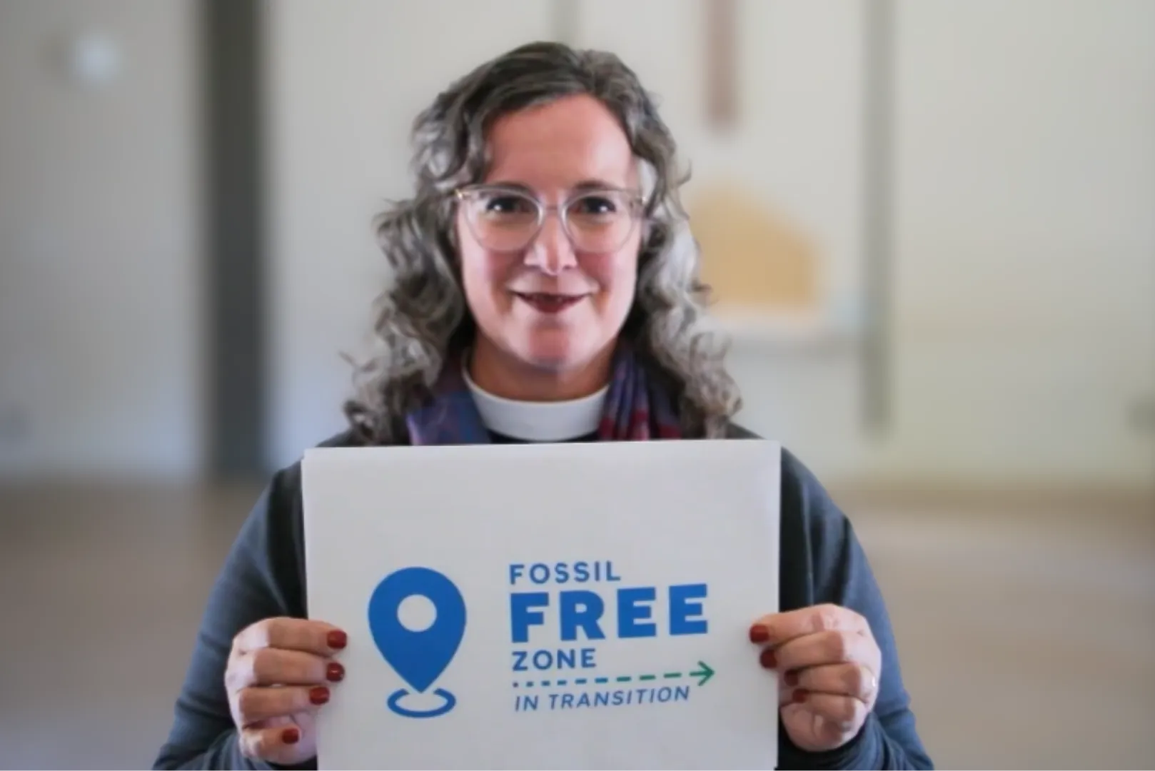 Woman holding sign pointing to fossil free zone in transition